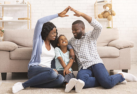 Hintergrundbild Versicherungsunternehmen zeigt eine fröhliche Familie im Wohnzimmer